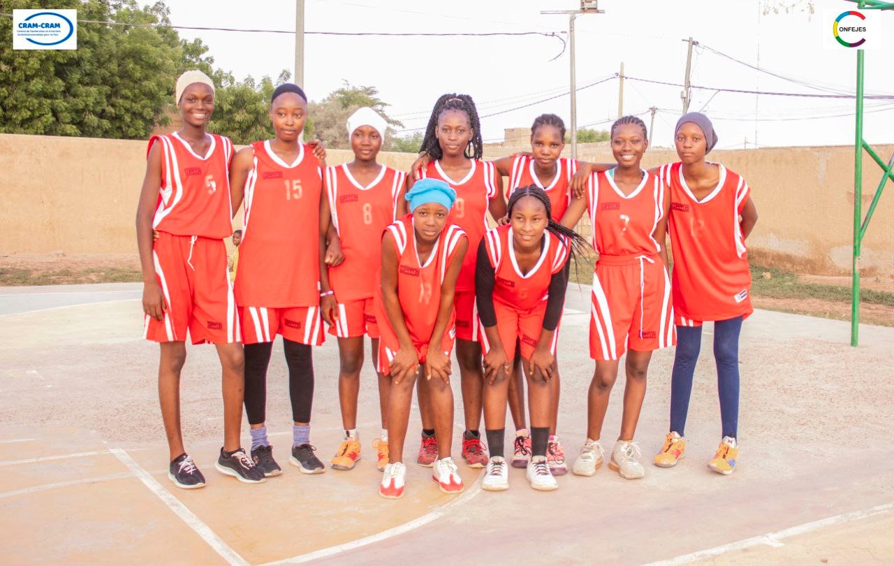 Une équipe féminine pose sur le terrain de basket-ball.