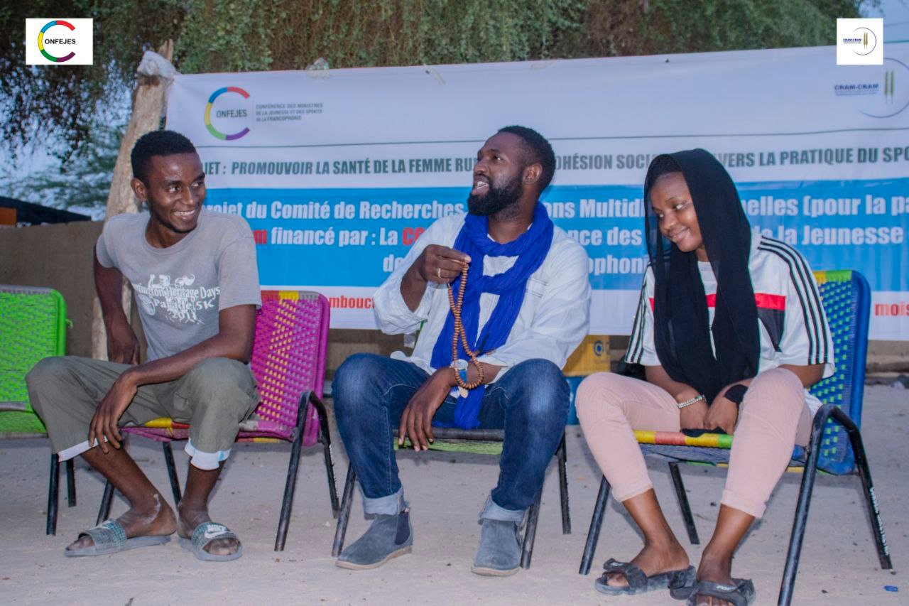 Trois intervenants animent une table ronde en plein air.