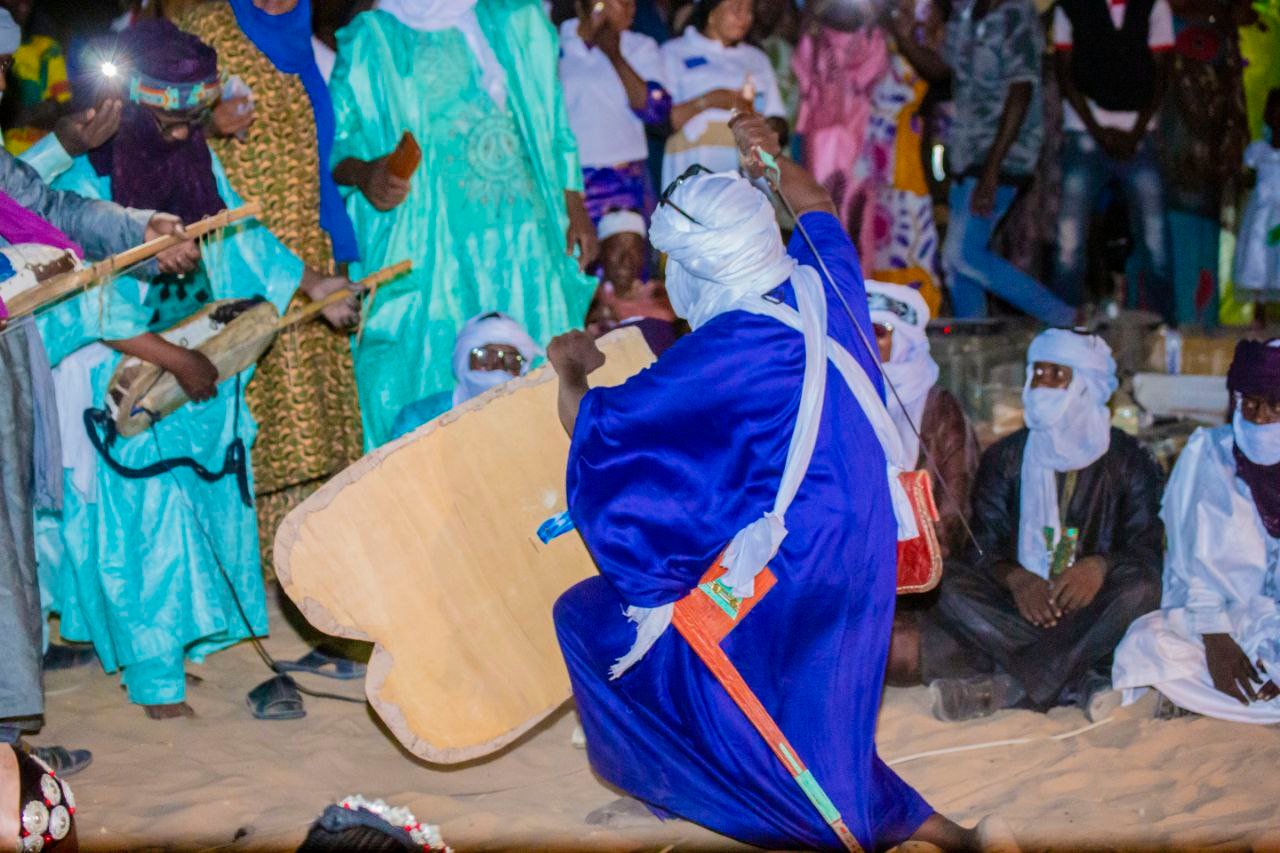 Un danseur en boubou bleu se produit au milieu des musiciens.