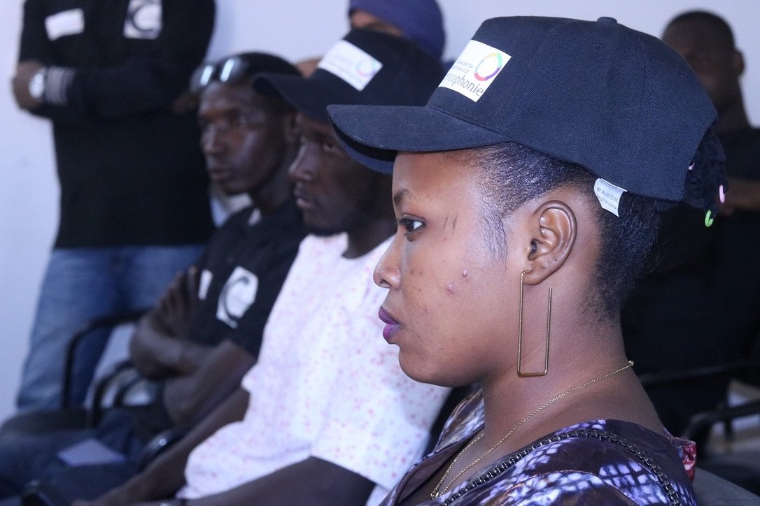 Des participants coiffés de casquettes suivent attentivement une séance en salle.